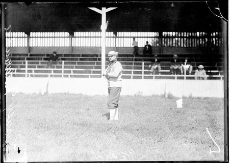 Milwaukee baseball player, Carney, holding a baseball bat, standing in front of grandstands on a baseball field - Chicago Daily News, Inc.