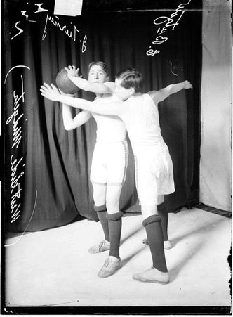 West Side Midgets basketball players E. Butzow and J. Tierney, standing in front of a dark backdrop - Chicago Daily News, Inc.