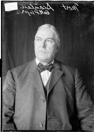 Baseball player Mort Scanlan, wearing a suit, sitting in front of a dark backdrop - Chicago Daily News, Inc.