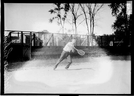 Lakeview tennis player Atkinson, holding a tennis racket and moving to his left, standing on a tennis court - Chicago Daily News, Inc.