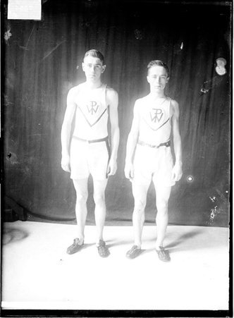 Wendell Phillips High School track athletes John Breathed and William Danne, standing in front of a dark backdrop - Chicago Daily News, Inc.