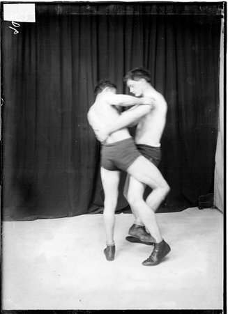 Wrestler performing a takedown on another wrestler by hooking his ankle behind his opponent's leg - Chicago Daily News, Inc.
