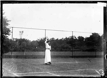 Tennis player, Mrs. Crane holding a tennis racket above her head, standing behind the baseline on a tennis court - Chicago Daily News, Inc.