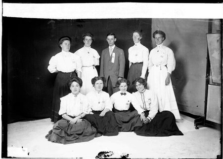 Edith Parks, Sarah Biggin, Maggie Bond, Agnes Kind, Daisy Jeffrey, H. Foster, and Grace Alison, posing in front of backdrop - Chicago Daily News, Inc.