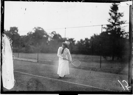 Tennis player, Mrs. Crane, leaning backwards, following through after swinging a racket, standing behind the baseline on a tennis court - Chicago Daily News, Inc.