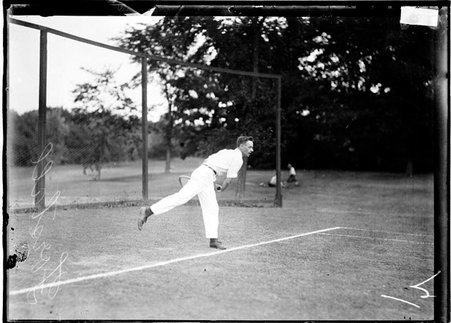 Tennis player, Forstall, following through after swinging a tennis racket, standing behind the baseline on a tennis court - Chicago Daily News, Inc.