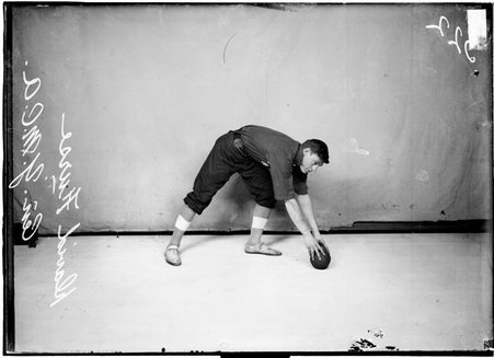 Indoor ball player, David Furse, Central YMCA, bending forward toward ball on floor - Chicago Daily News, Inc.