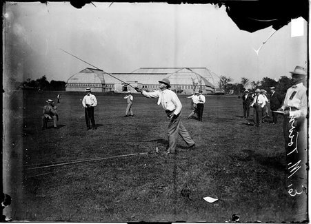 Caster, E. M. Town lunging forward with fly rod in front of him, standing on grass near Botanic Gardens - Chicago Daily News, Inc.