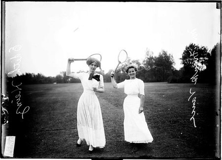 Tennis players, Edith Heinz and Mrs. Frank Vance, standing, facing the camera, holding racquets over shoulders on tennis court - Chicago Daily News, Inc.