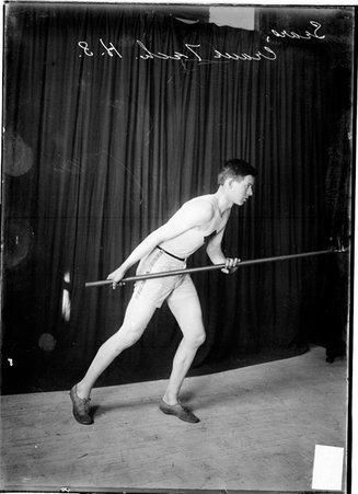 Athlete, Sears, Crane Technical High School, posing as if running with a pole in front of dark backdrop - Chicago Daily News, Inc.