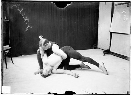Wrestlers, J. Winholtz and C. H. Bragg, with Winholtz holding Bragg in front of dark background - Chicago Daily News, Inc.