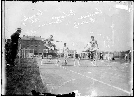 Track athletes, Gardener, Cramley, and Richards, Purdue, Cramley jumping over hurdles during race at Marshall Field - Chicago Daily News, Inc.