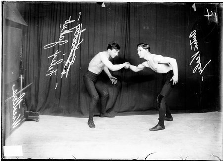 Wrestlers, Anton Vessley and Felex Jakub, Cornell Square wrestlers, shaking each other's hands in front of dark background - Chicago Daily News, Inc.