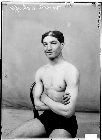 Fighter, Willie Schaeffer, sitting with arms crossed on chest against plain backdrop - Chicago Daily News, Inc.
