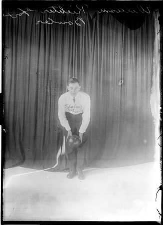 Bowler, William Richter, leaning forward, holding ball in front of knees in front of dark background - Chicago Daily News, Inc.