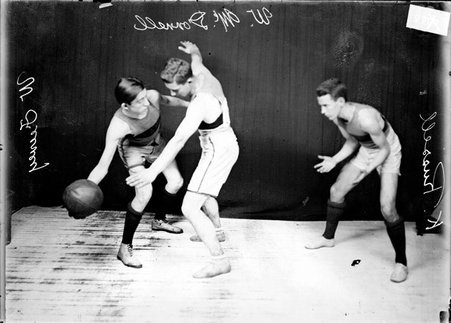 Oak Park High School basketball posing with Feeney, guarded by McDonnell, preparing to pass the ball to Russell. - Chicago Daily News, Inc.