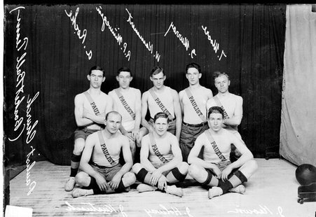Paulist Church basketball team posing in front of a dark colored background - Chicago Daily News, Inc.