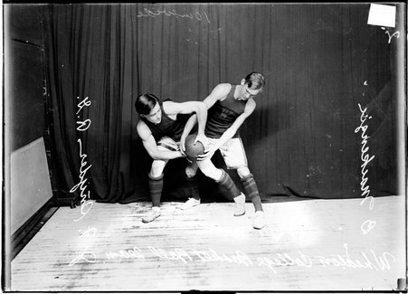 Wheaton College basketball players J. F. Snyder and B. Mackenzie posing, struggling for possession of the ball - Chicago Daily News, Inc.