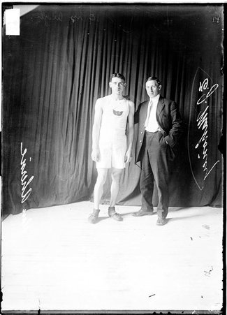 Athletes, Dan Aherne and J. Mahoney standing in front of dark backdrop - Chicago Daily News, Inc.