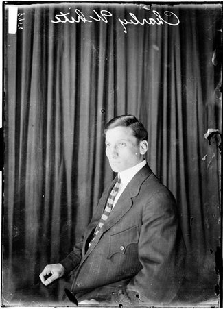 Fighter, White sitting left side to camera against dark background, wearing dark suit and striped tie - Chicago Daily News, Inc.