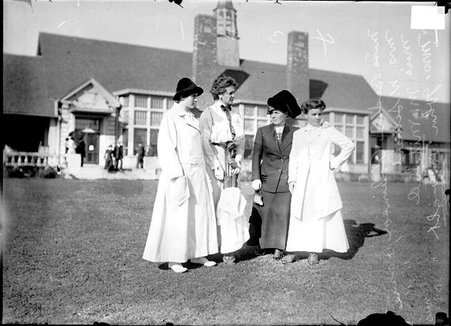 Golfers, Miss B. Robinson, Mrs. W. Seward, Miss M. Mitchell and Mrs. John Dwight standing on the grass in front of the clubhouse at the Homewood Golf Links - Chicago Daily News, Inc.