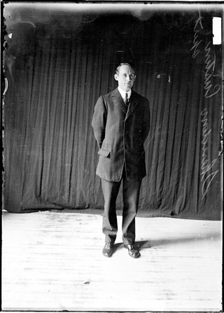 Sheridan Custin, associated with Chicago sports, standing in front of a dark colored background - Chicago Daily News, Inc.