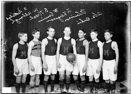 McKinley High School basketball team players standing in front of a dark colored background, Erwin holding a basketball - Chicago Daily News, Inc.