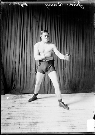 Boxer Jim Barry standing in a boxing stance, facing the camera with his arms pointing toward the right side of the image - Chicago Daily News, Inc.