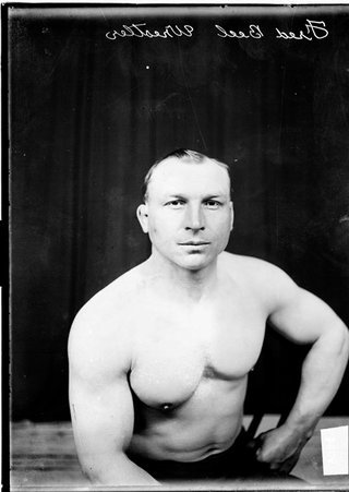 Wrestler Fred Beell sitting in a chair in front of a dark colored background - Chicago Daily News, Inc.