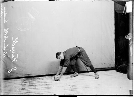 De LaSalle indoor baseball player J. Farrell holding a ball bending to the left of the image standing in front of a light colored background - Chicago Daily News, Inc.