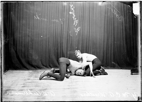 YMCA wrestlers holding Ackerman by the shoulders and head close to the floor of the room - Chicago Daily News, Inc.
