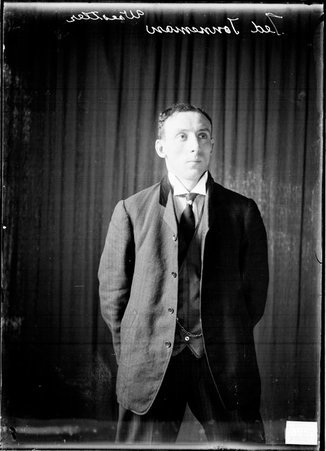 Wrestler Ted Tonneman standing with his hands behind his back in front of a dark colored background - Chicago Daily News, Inc.