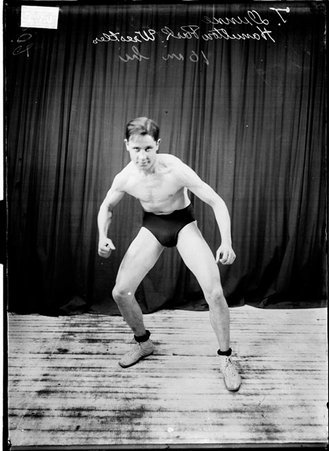 Hamilton Park wrestler T. Dunn standing in a wrestling stance facing the camera in front of a dark colored background - Chicago Daily News, Inc.