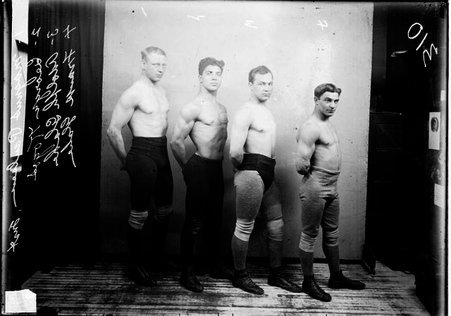 Wrestlers, Kogos, Paulsen, and Glahe, standing in a row in front of a light colored background - Chicago Daily News, Inc.