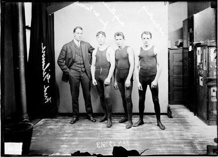 Pugilists, Jim McGovern, Art Armstrong, and Andy Dans, and manager Fred Gilmore standing in front of a light-colored backdrop - Chicago Daily News, Inc.