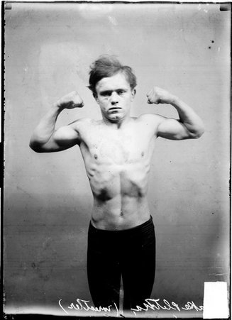 Wrestler, Jake Pletka flexing his biceps - Chicago Daily News, Inc.