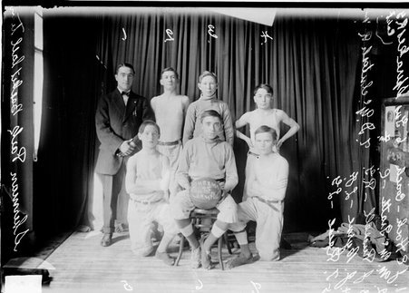 Basketball team, Sherman Park, gathered in two rows against a dark curtain - Chicago Daily News, Inc.
