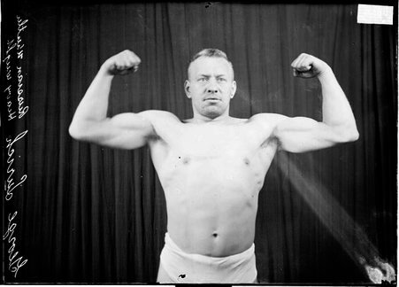 Wrestler, George Lurich flexing his biceps with his arms raised at his sides - Chicago Daily News, Inc.
