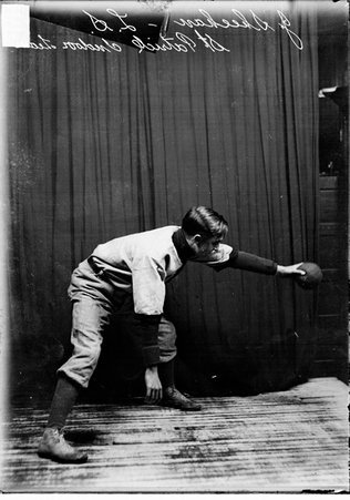 Indoor baseball player, J. Sheehan, St. Patrick's, holding a ball in his left hand, standing in front of a dark colored background - Chicago Daily News, Inc.