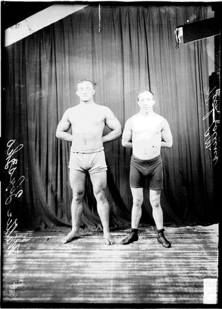 Wrestlers, Walter Zbysczko and Nick Collins standing in front of a dark backdrop - Chicago Daily News, Inc.