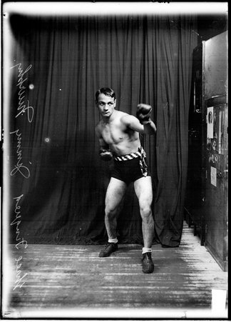 Pugilist, Jimmy Murphy, throwing a left jab, standing in a boxing stance in front of a dark backdrop - Chicago Daily News, Inc.