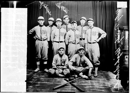 Indoor baseball team, Holy Trinity High School posing in front of a dark backdrop - Chicago Daily News, Inc.
