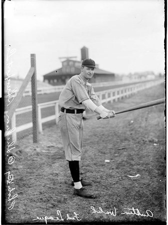 Baseball player, Austin Walsh, Chicago Whales, posing in batting stance by a racetrack fence - Chicago Daily News, Inc.