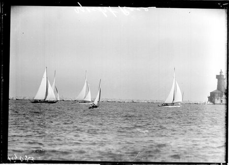 Yachts sailing on Lake Michigan near a breakwater and lighthouse - Chicago Daily News, Inc.