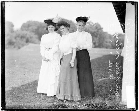 Golfers Mrs. J. S. Sheehan, Grace Anthony, and Nellie Anthony standing in the shade of a structure on an unidentified golf course - Chicago Daily News, Inc.