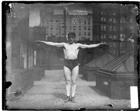 Pugilist Tommy Burns holding his arms out at his sides, standing on the roof of a building - Chicago Daily News, Inc.