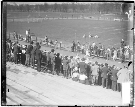Athlete running on an athletic track, viewed from the bleachers - Chicago Daily News, Inc.