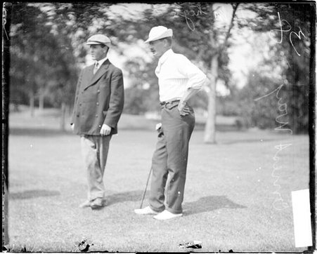 Golfer, Ernest Way, leaning on a golf club, standing with an unidentified man on the grounds of an unidentified golf course - Chicago Daily News, Inc.