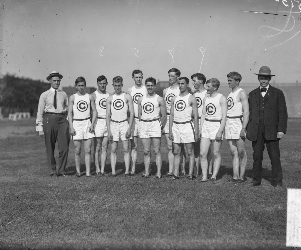Track and field athletic team, many smiling, posing with two men wearing street clothes on Marshall Field at the University of Chicago - Chicago Daily News, Inc.