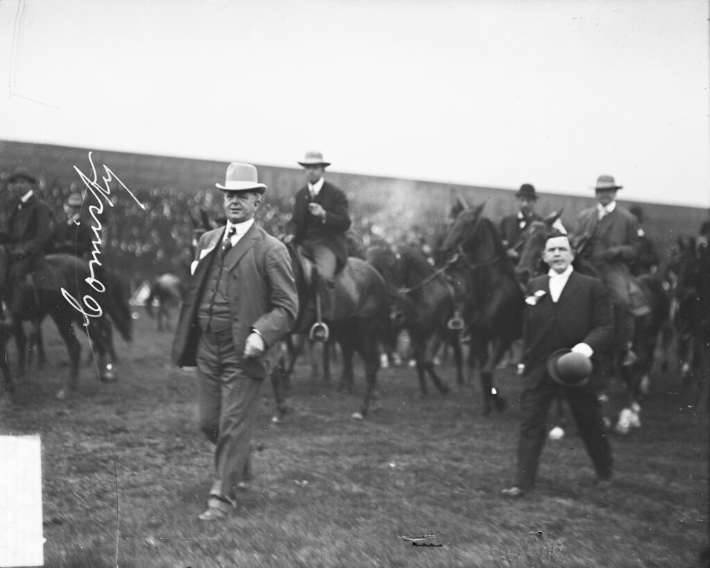 Charles Comiskey, owner of the American League's Chicago White Sox baseball team, walking on the field, with men riding horses in background - Chicago Daily News, Inc.